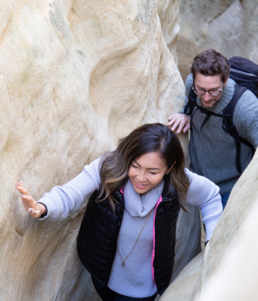 Discovering the beauty of San Diego hikes, a smiling woman and man navigate sandstone slot canyons.