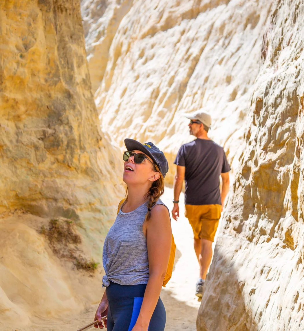 Woman looks up to the walls from the floor of the slot canyon