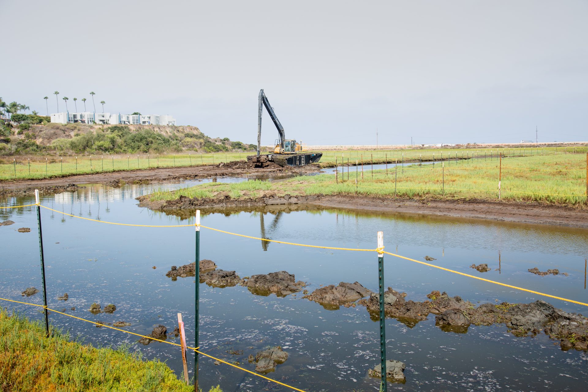 photo of excavator in the lagoon dredging mud