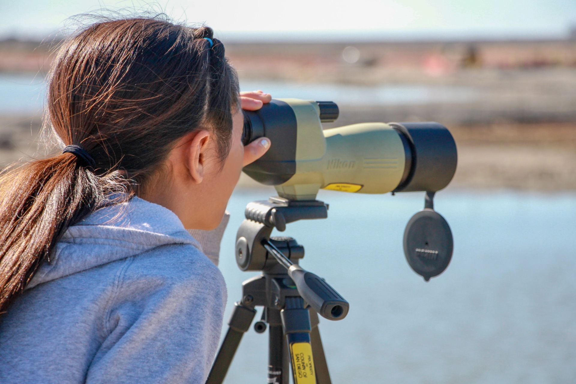 Student looking through binoculars to observe birds