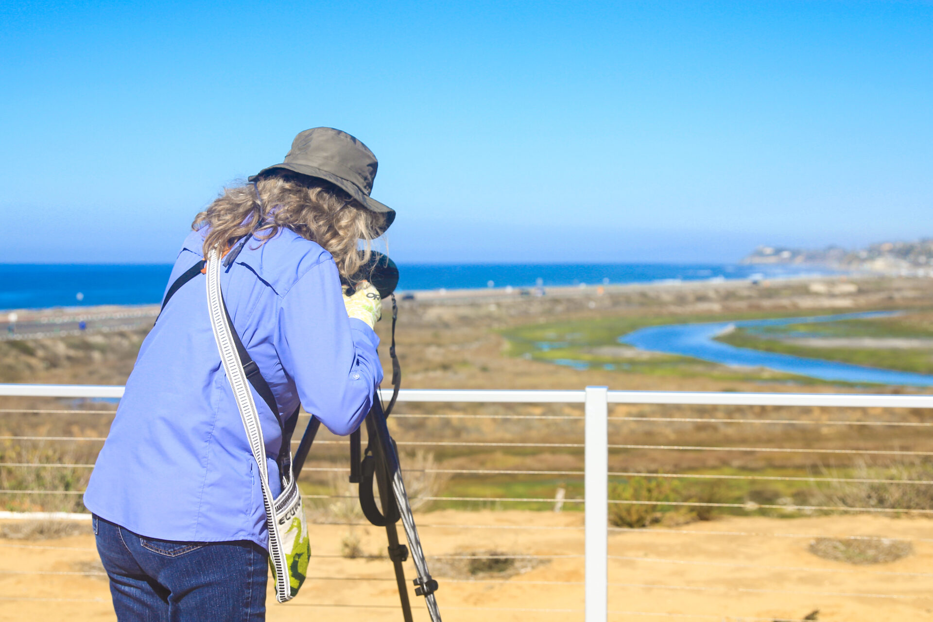 Personal looking through a birding scope at ocean and mudflats